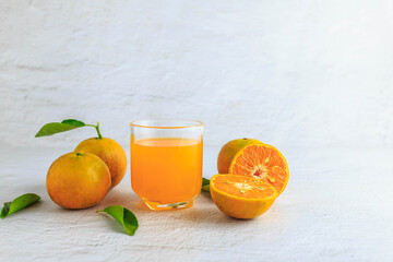 .Freshly squeezed orange juice in a glass and fresh citrus fruits on a white background.