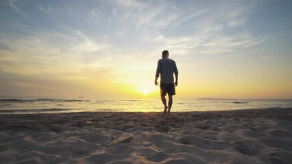 Silhouette of young man with raised hands at sunset sandy beach, concept of success and victory. Achievement and successful pose