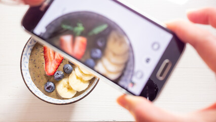 Food blogger work,  healthy lifestyle making a photo of a vegan breakfast bowl smoothie with banana...