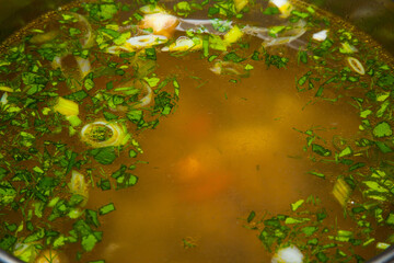 Soup with meatballs, vegetables, herbs and egg in a pan close-up.