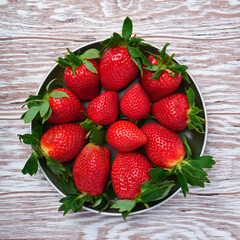 Ceramic plate full of fresh strawberries on wood table
