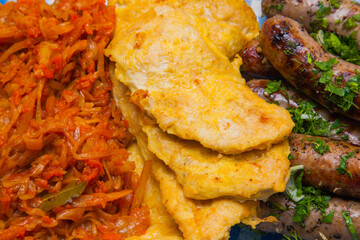Braised cabbage with bay leaf, fried chicken chop in egg batter and fried meat sausages sprinkled with garlic, parsley and dill.