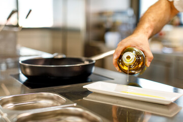 mano di un cuoco versa dell'olio d'oliva in una ciotola 