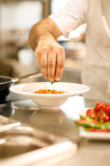 condimento di un piatto di pasta con il sugo da parte di un cuoco in cucina