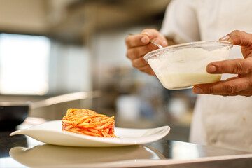 condimento di un piatto di pasta con il sugo e pesto da parte di un cuoco in cucina