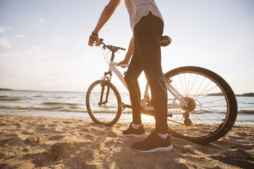 Fototapeta na wymiar man with a bicycle standing on a sandy beach .