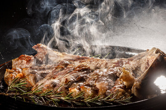 bistecca fumante sulla griglia che la cuoce, isopaltra su sfondo nero 