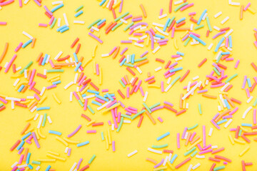 Colorful festive sugar sprinkles  on yellow background. Flat lay style. Top view. Place for design. Easter background.