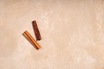 Two cinnamon sticks lie on a beige background