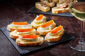 crostini di pane con formaggio e salmone serviti su un tagliere su un tavolo in legno 