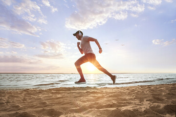 Fototapeta na wymiar sporty man running on a sandy beach at sunset .