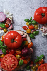 Flat lay composition of different tomatoes, onion, basil and garlic	