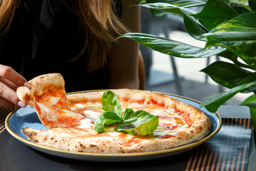 pizza tonda  farcita  servita su un piatto in un tavolo di una pizzeria mentre un sperona mangia...