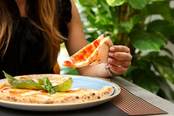 pizza tonda  farcita  servita su un piatto in un tavolo di una pizzeria mentre un sperona mangia...