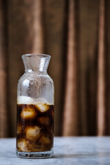 Cold coffee with ice and milk. Iced coffee with ice in a glass transparent elongated glass with