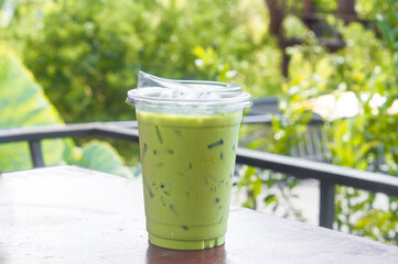 Iced matcha latte or green milk tea in plastic glass served at coffee shop or coffeehouse among nutural environment in upcountry