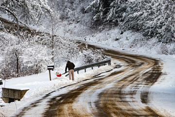 A man shovels out his mailbox after the plows came through and piled it high at the end of his...