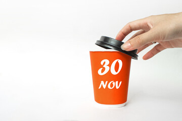 November 30th. Day 30 of month, Calendar date. A woman's hand open black plastic cap of red disposable cardboard coffee paper cup with Calendar Date. Autumn month, day of the year concept.
