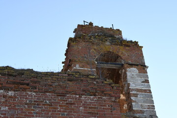 Ruins of an old church. Red bricks and remnants of plaster on a decrepit building. The skeleton of the building against the blue sky. 