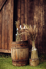 Wedding decorations with dry grass, wooden barrel and candles in boho style