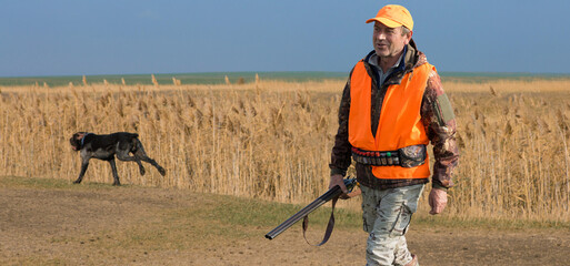 Hunter man in camouflage with a gun during the hunt in search of wild birds or game. Autumn hunting...