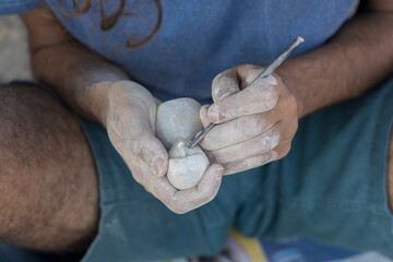 Male hands carve stone sculpture in India,