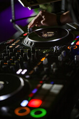 Fototapeta na wymiar Close up of DJ hands controlling a music table in a night club