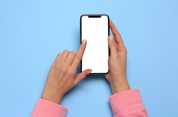 Woman using smartphone on light blue background, top view