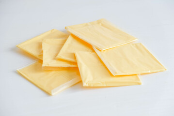 Separately packed cheese slices on a white wooden table background