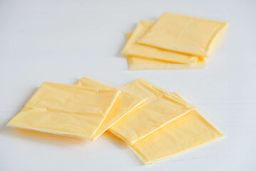 Separately packed cheese slices on a white wooden table background