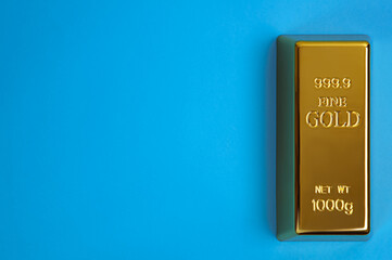 An ingot of gold metal bullion of pure brilliant diagonally located on a blue background.