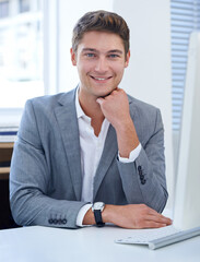 Enjoying his job to the fullest. A satisfied young businessman sitting at his desk.