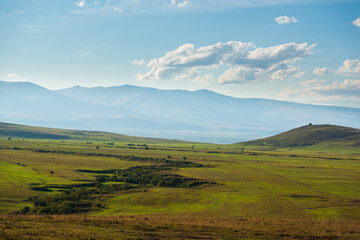 Field landscape with winding road and mountains