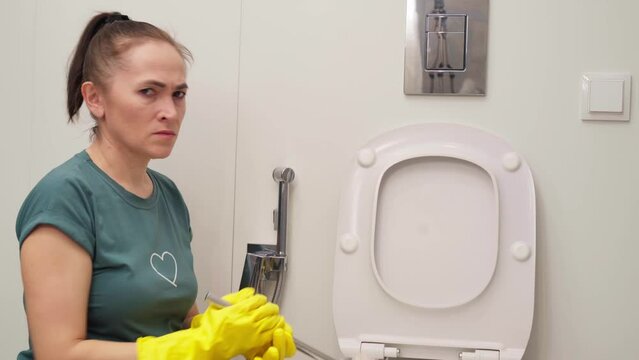 woman covering nose to avoid bad smell while cleaning a smelly toilet bowl
