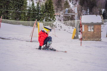 Child skiing in mountains. Active toddler kid with safety helmet, goggles and poles. Ski race for young children. Winter sport for family. Kids ski lesson in alpine school. Little skier racing in snow