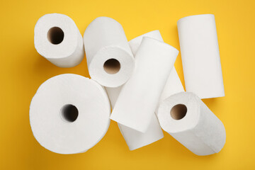 Many rolls of paper towels on yellow background, flat lay