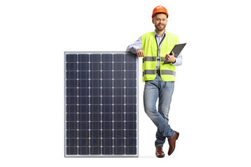 Full length portrait of a male engineer leaning on solar cell panel and holding a clipboard