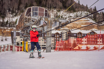 Boy uses a training lift. Child skiing in mountains. Active toddler kid with safety helmet, goggles and poles. Ski race for young children. Winter sport for family. Kids ski lesson in alpine school