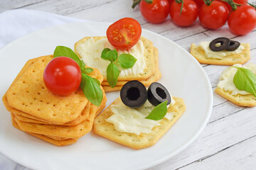 Fototapeta na wymiar Crunchy crackers with cream cheese, tomatoes and olives.