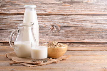 Vegan non diary buckwheat milk in glass, bottle and jug with buckwheat groats on a wooden background. Vegan buckwheat drink is plant based alternative milk . Veggies healthy milk product, copy space