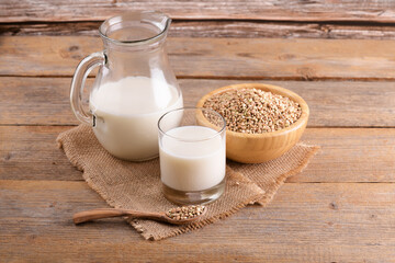 Vegan non diary buckwheat milk in glass, bottle and jug with buckwheat groats on a wooden background. Vegan buckwheat drink is plant based alternative milk. Veggies healthy milk product, close up