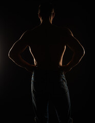 Fototapeta na wymiar Silhouette of topless guy posing from the back in studio