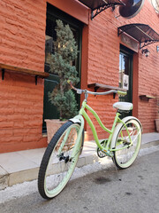 Fototapeta na wymiar retro green bicycle parked near cafe with red break wall