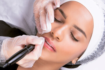 Young woman receiving permanent lip makeup treatment, vertical shoot 