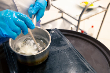 top view of a ladle of boiling water, the cook stirs a poached egg with a spoon