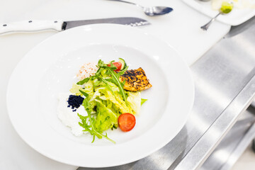 a large plate with lettuce and black caviar. cooked salad on the table
