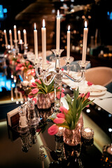 Festive table setting with candles and flowers. pink tulips