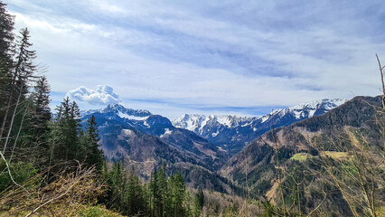 Obraz premium Scenic view of snow capped mountain peaks of Karawanks near Sinacher Gupf in Carinthia, Austria. Mount Wertatscha and Hochstuhl (Stol) is visible in early spring. Hills in Rosental on sunny day. Hike