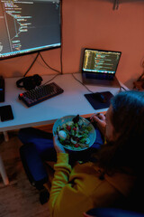 Male IT developer eating salad while programming