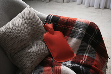 Rubber hot water bottle and checkered plaid on armchair indoors